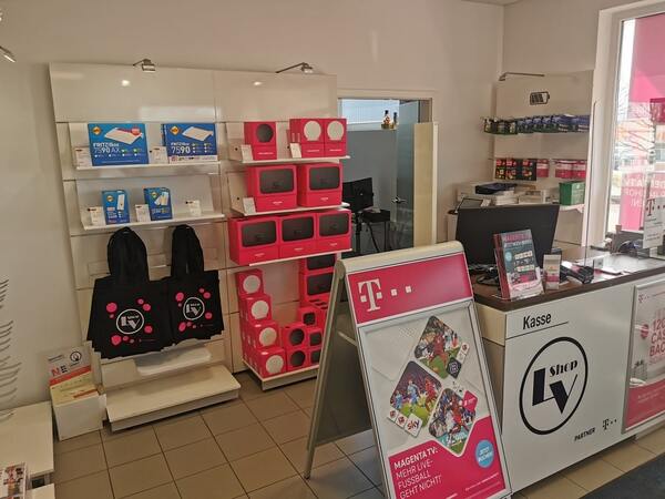 Telekommunikationsladen mit FRITZ!Box-Routern, Magenta TV Werbung und Kasse im Vordergrund.
