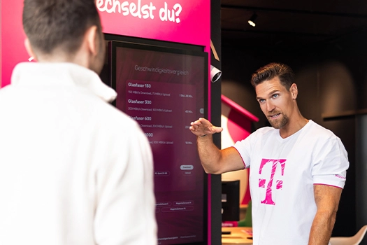 Telekom Mitarbeiter erklärt Glasfaser-Internet im Telekom Shop am Bildschirm